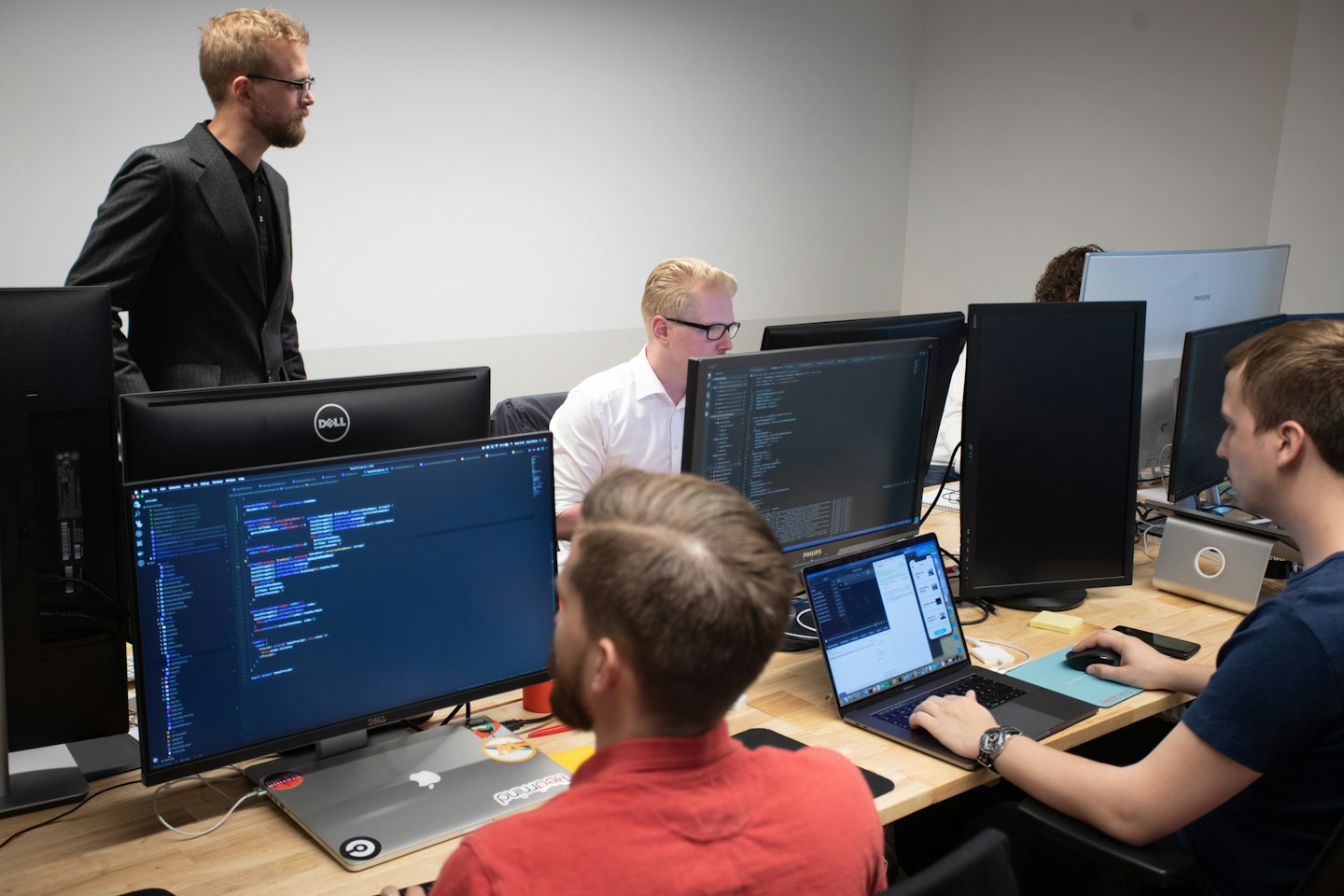 Software developers working at computer workstations in a modern office.